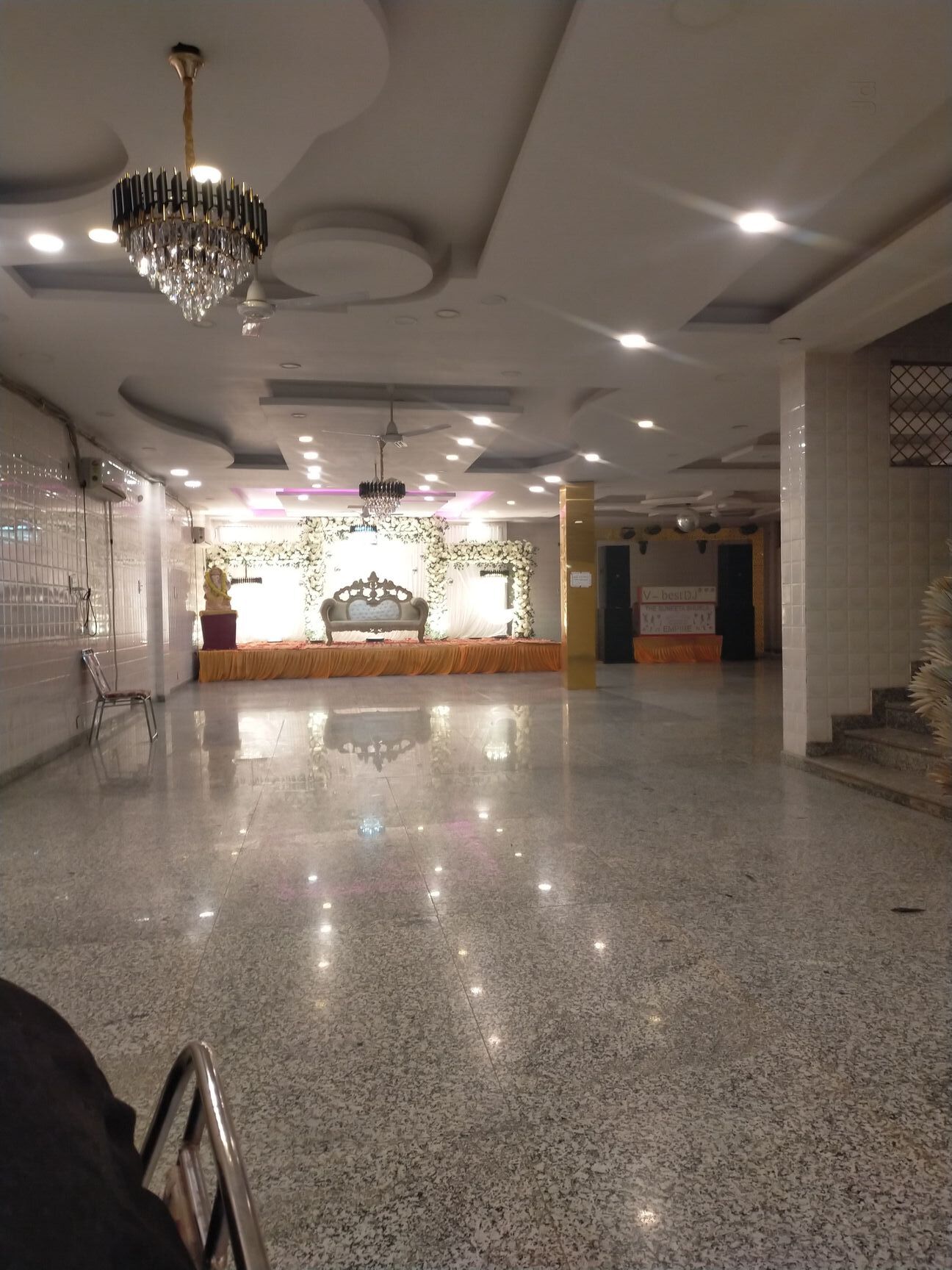 Banquet hall stage with white floral backdrop and chandelier